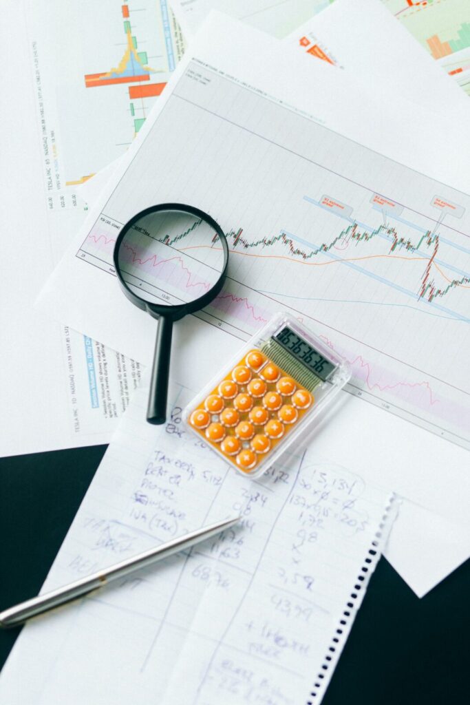 Lupa, calculadora e gráficos financeiros sobre a mesa