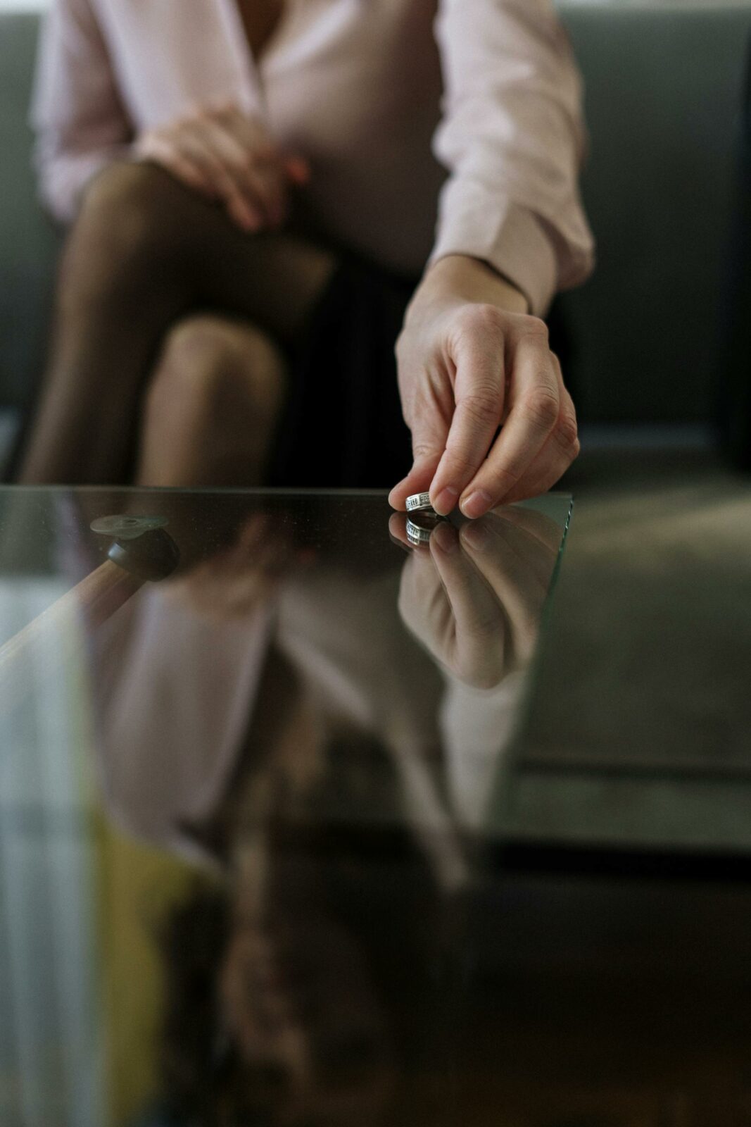 Mulher deixando a aliança sobre uma mesa de vidro